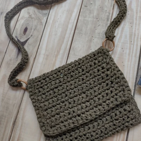 BOLSA NA COR VERDE MUSGO COM DETALHES DE POÁ EM PRETO, ALÇAS PRESAS COM ARGOLAS DE MADEIRA.